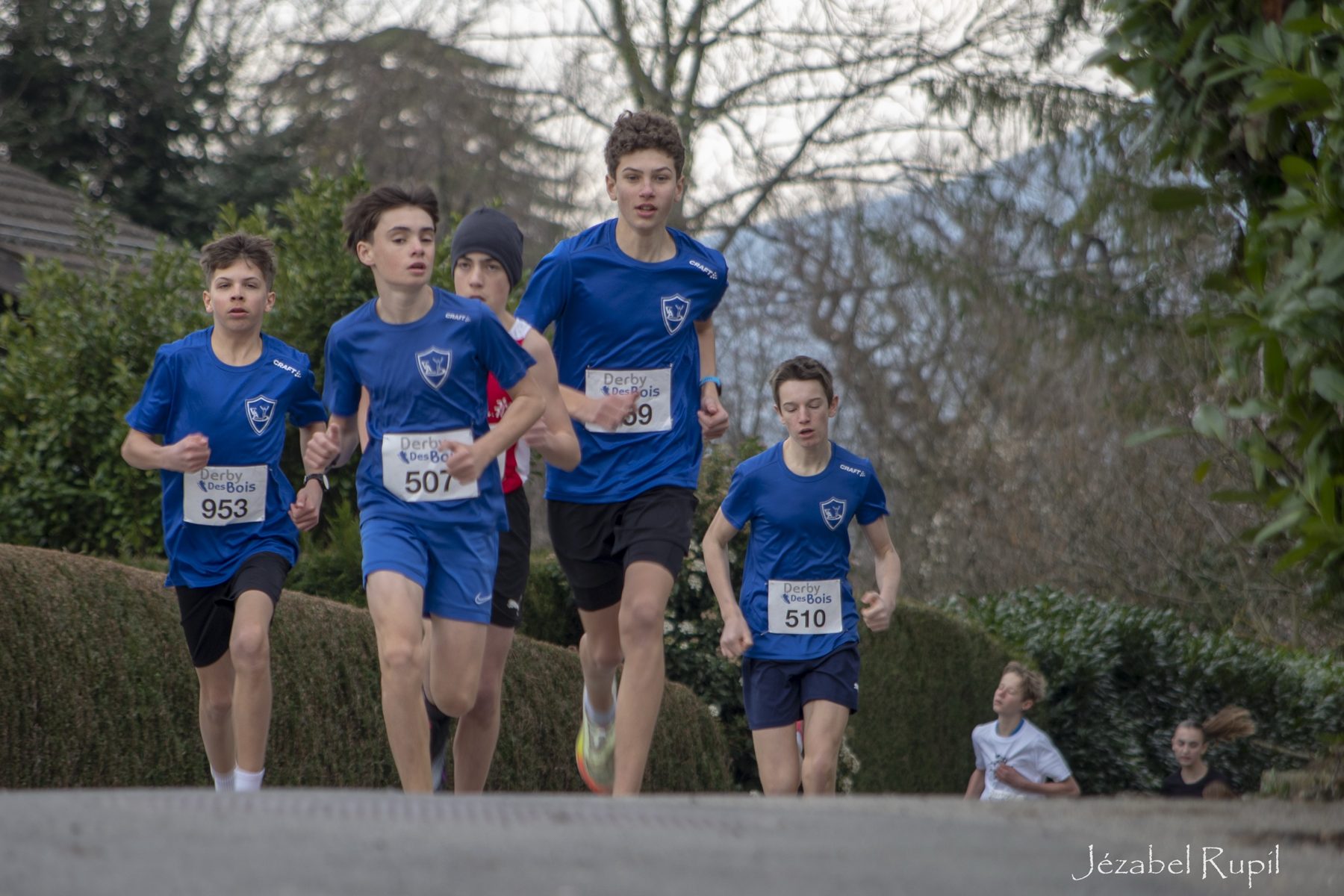 Des jeunes coureurs en maillot bleu attaquent une montée du Derby des Bois